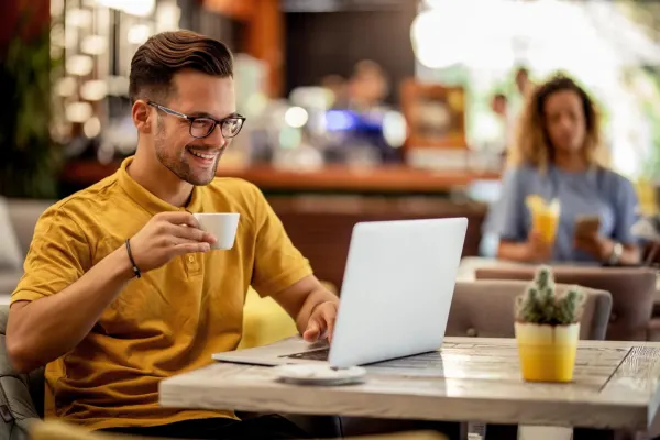 Freelancer working on a laptop in a café while enjoying coffee, managing clients, projects, and online business tasks.