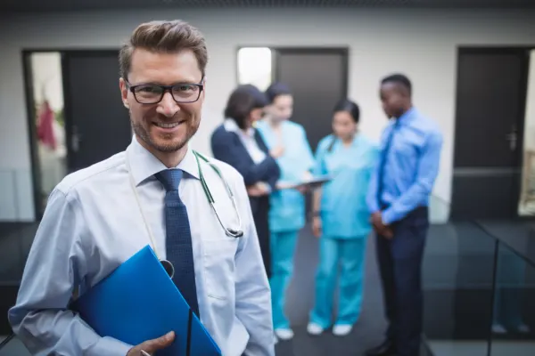 Smiling doctor holding a folder in a modern clinic background representing professional Healthcare Businesses.
