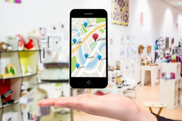 A hand holding a smartphone with a map display featuring location pins inside a store, illustrating local SEO mistakes.
